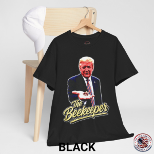 Black T‑shirt featuring a pop‑art grunge illustration of President Trump holding a bee in his hand with bold ‘The Beekeeper’ text below.