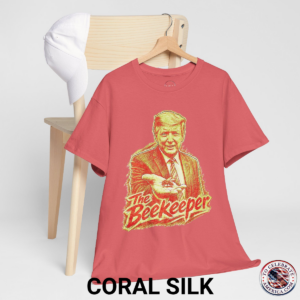 Coral Silk T‑shirt featuring a pencil‑sketch illustration of President Trump holding a small bee in an outstretched hand, with stylized ‘The Beekeeper’ text below.