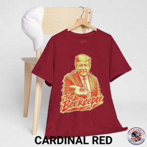 Cardinal Red T‑shirt featuring a pencil‑sketch illustration of President Trump holding a small bee in an outstretched hand, with stylized ‘The Beekeeper’ text below.