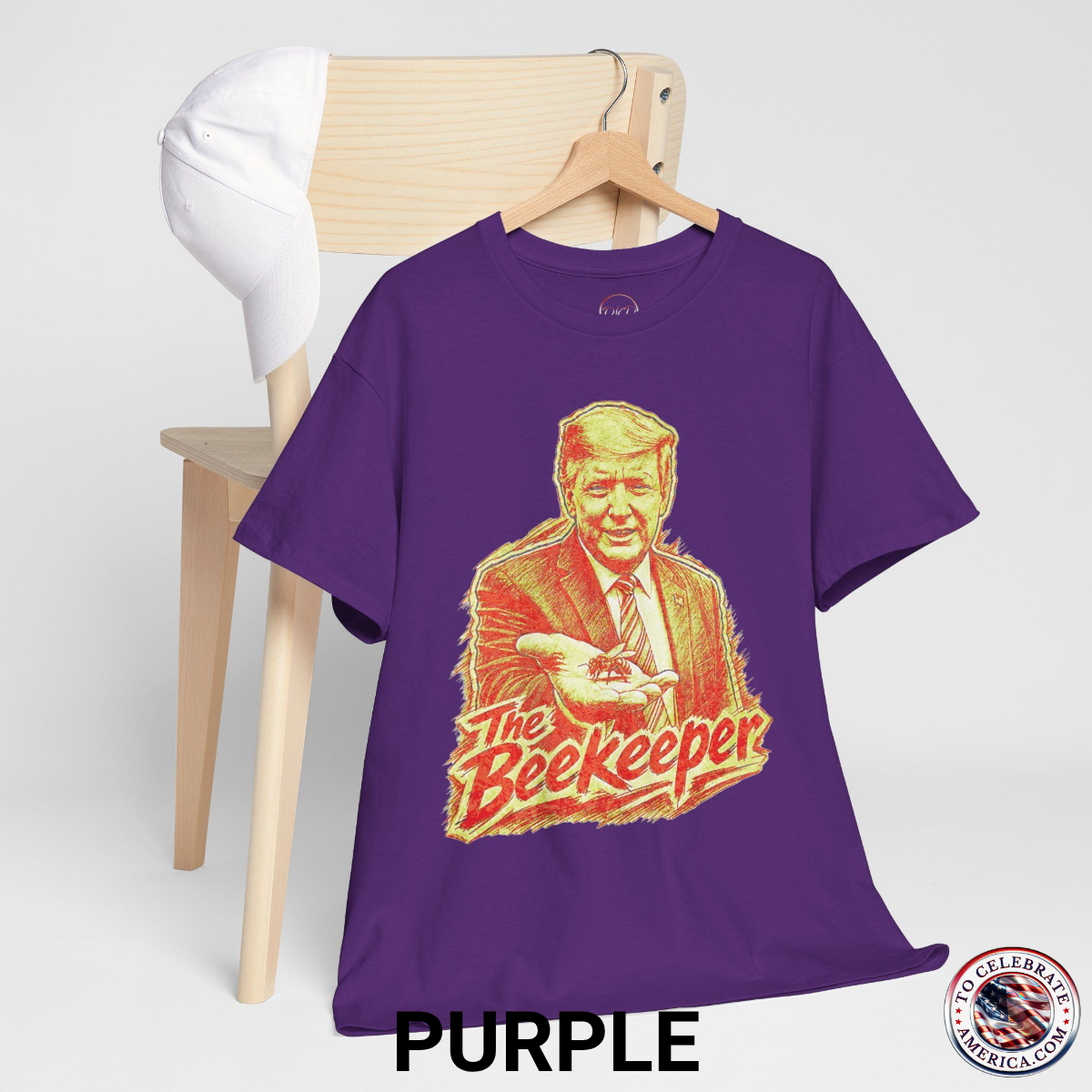 Purple T‑shirt featuring a pencil‑sketch illustration of President Trump holding a small bee in an outstretched hand, with stylized ‘The Beekeeper’ text below.