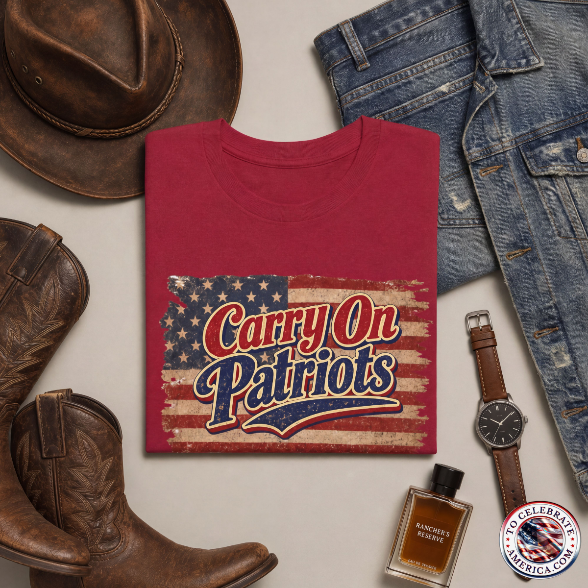 Antique Cherry Red T‑shirt featuring distressed American flag background with bold ‘Carry On Patriots’ vintage lettering. Set against masculine wearing apparel featuring a leather cowboy hat, blue jeans, jean jacket, cowboy boots, a stylish yet subtle watch and a bottle of cologne.